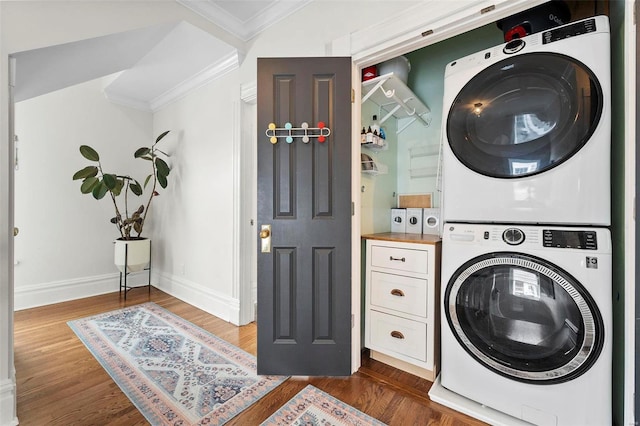 clothes washing area with ornamental molding, dark wood-type flooring, and stacked washer / dryer