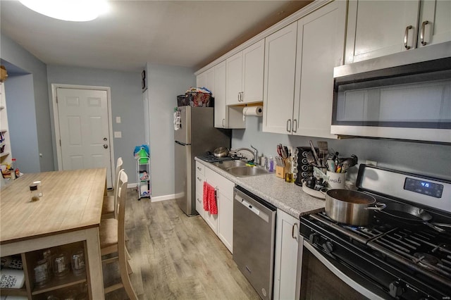 kitchen featuring stainless steel appliances, sink, white cabinets, and light hardwood / wood-style floors