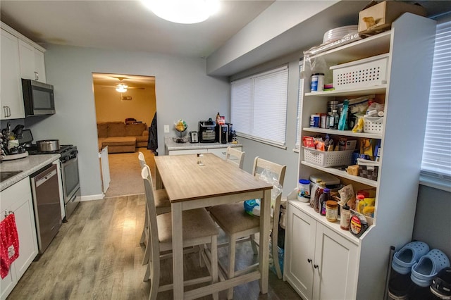 kitchen with white cabinetry, ceiling fan, stainless steel appliances, and light hardwood / wood-style flooring