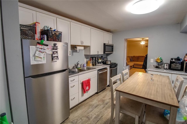 kitchen with sink, white cabinetry, light hardwood / wood-style flooring, ceiling fan, and stainless steel appliances