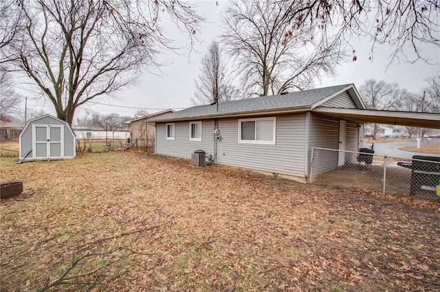 back of property featuring a carport, central AC unit, and a shed