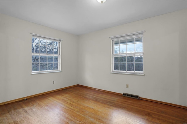 spare room featuring hardwood / wood-style flooring and a healthy amount of sunlight