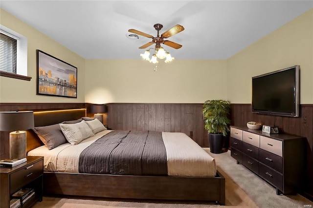 carpeted bedroom featuring ceiling fan and wooden walls