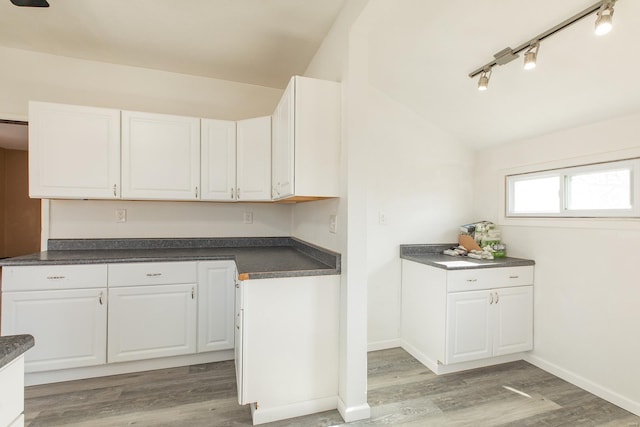 kitchen with hardwood / wood-style flooring, lofted ceiling, track lighting, and white cabinets