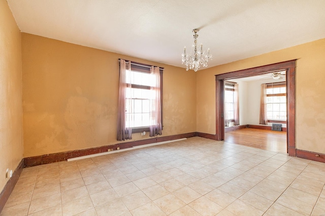 spare room with a wealth of natural light, a chandelier, and light tile patterned floors