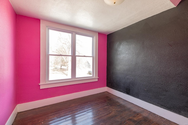 unfurnished room featuring a textured ceiling and dark hardwood / wood-style flooring