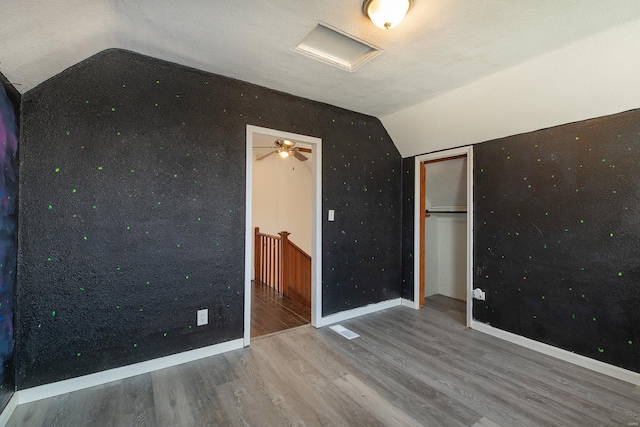 unfurnished bedroom with vaulted ceiling, hardwood / wood-style floors, a textured ceiling, and a closet