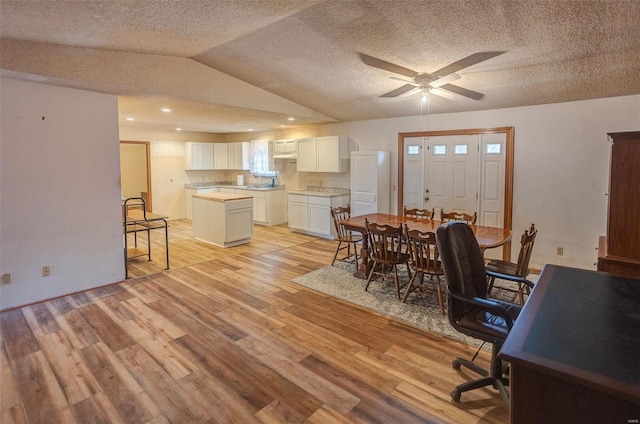 office area featuring ceiling fan, vaulted ceiling, light hardwood / wood-style flooring, and a textured ceiling