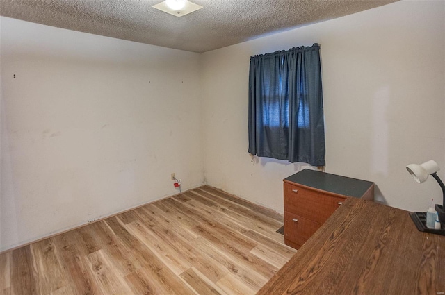 empty room with a textured ceiling and light wood-type flooring