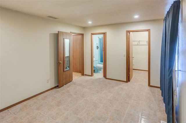 unfurnished bedroom featuring a spacious closet and ensuite bathroom