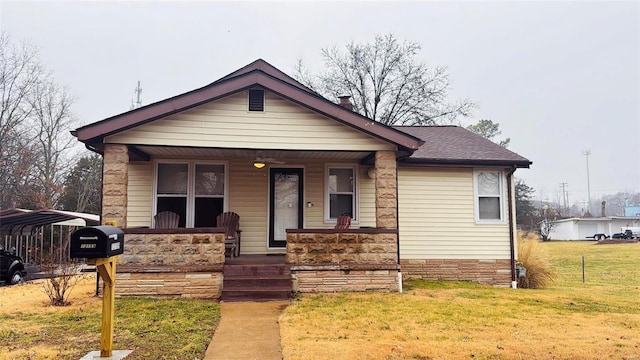 bungalow with a porch, a carport, and a front lawn