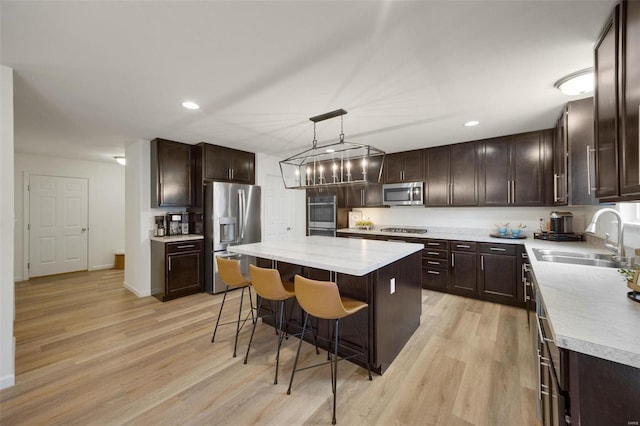 kitchen featuring a center island, decorative light fixtures, light countertops, appliances with stainless steel finishes, and a sink