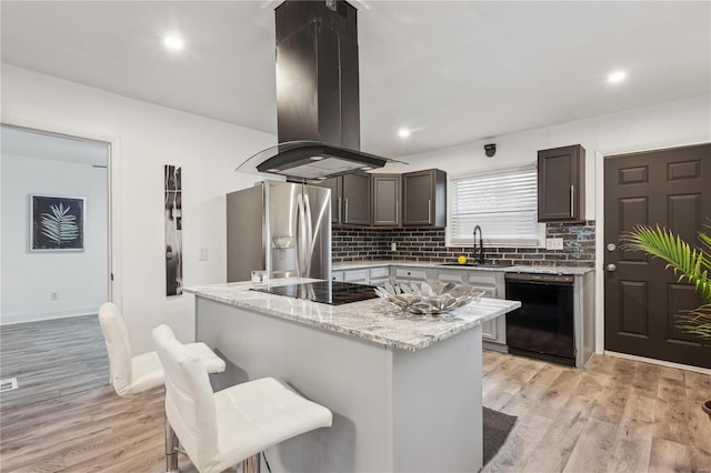 kitchen featuring island range hood, light hardwood / wood-style floors, sink, and black appliances