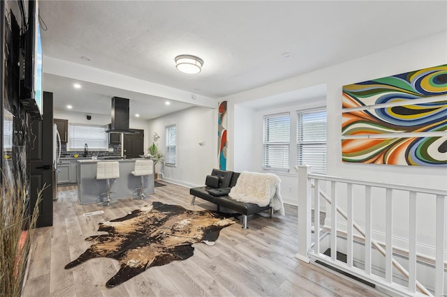 living room with sink, light hardwood / wood-style flooring, and a wealth of natural light