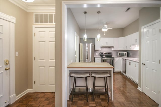 kitchen with white cabinetry, wooden counters, appliances with stainless steel finishes, a kitchen breakfast bar, and dark parquet floors