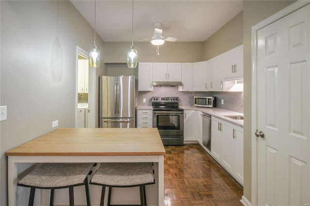 kitchen featuring white cabinetry, tasteful backsplash, appliances with stainless steel finishes, and dark parquet floors