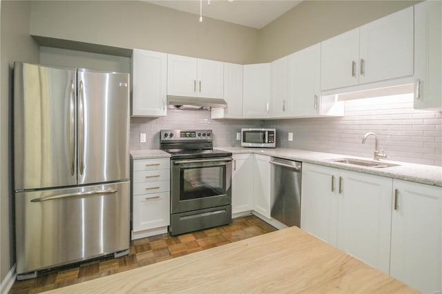 kitchen with tasteful backsplash, sink, white cabinets, and appliances with stainless steel finishes