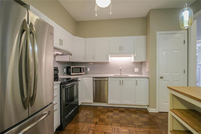 kitchen featuring appliances with stainless steel finishes, decorative light fixtures, white cabinetry, sink, and dark parquet flooring