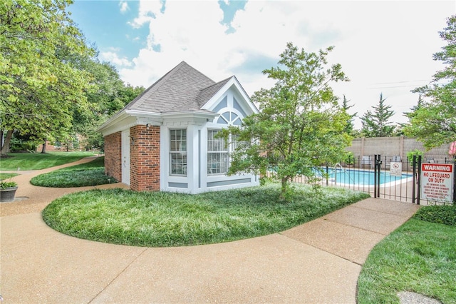 view of side of property with a community pool, an outbuilding, and a lawn