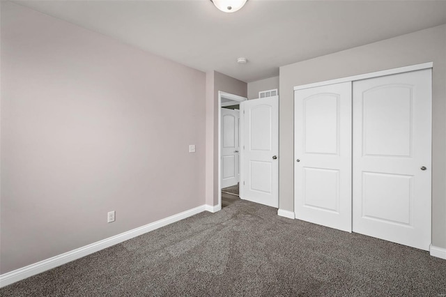 unfurnished bedroom featuring a closet, dark carpet, visible vents, and baseboards