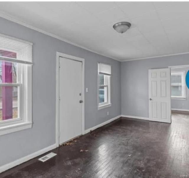 foyer entrance with crown molding, plenty of natural light, and dark hardwood / wood-style floors