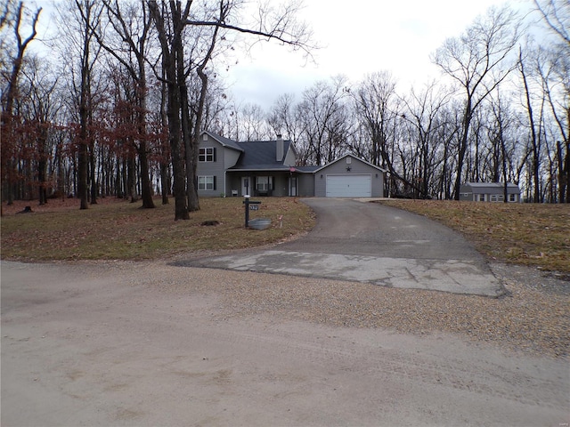 view of front of property featuring an attached garage, driveway, and a chimney