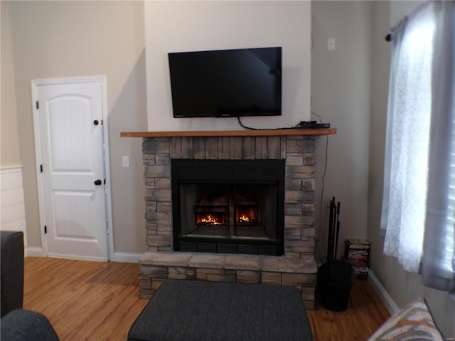 living room featuring a fireplace, baseboards, and wood finished floors