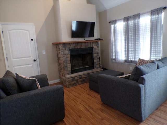 living area featuring a fireplace, baseboards, and wood finished floors