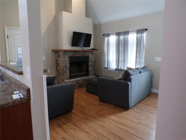 living room with a fireplace, a towering ceiling, baseboards, and wood finished floors