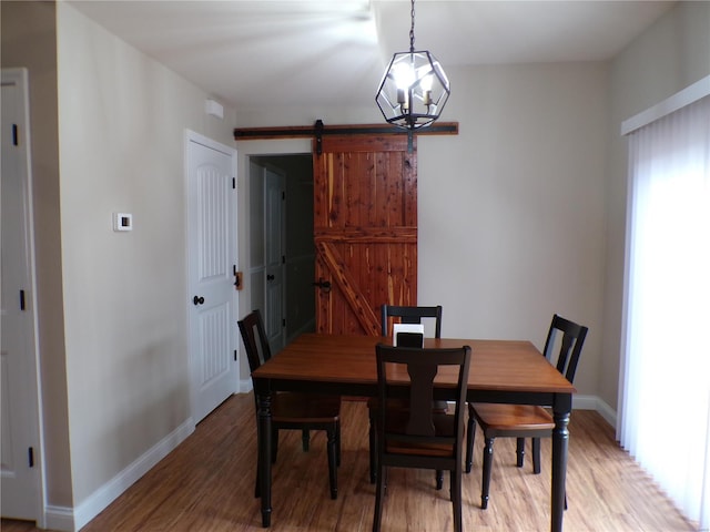 dining space featuring a barn door, baseboards, and wood finished floors