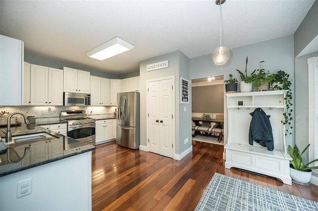 kitchen featuring decorative light fixtures, white cabinetry, sink, dark hardwood / wood-style flooring, and stainless steel appliances