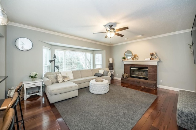 living room featuring dark wood-type flooring, ceiling fan, a fireplace, and crown molding