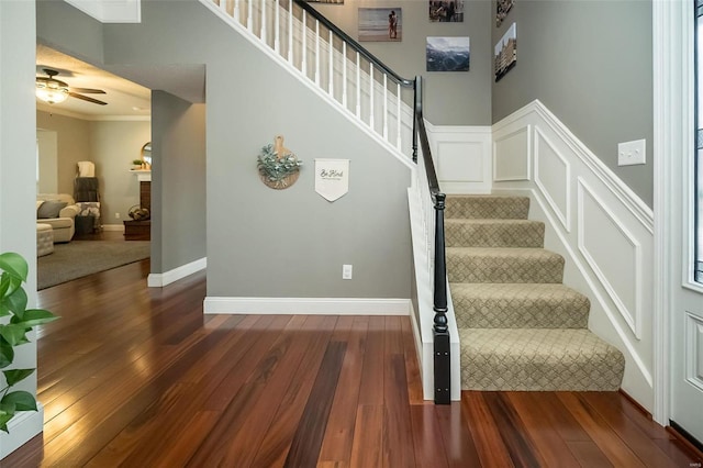 staircase with ceiling fan, ornamental molding, and hardwood / wood-style floors