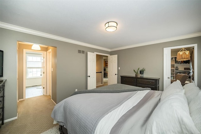 carpeted bedroom with crown molding, a walk in closet, and a closet