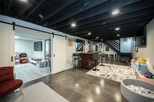 basement featuring a barn door, stainless steel fridge, and indoor bar