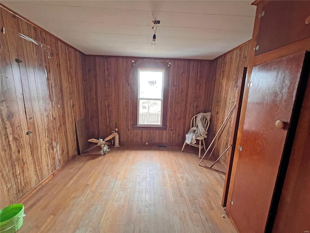 spare room with light hardwood / wood-style floors and wood walls