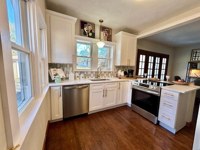 kitchen with pendant lighting, sink, appliances with stainless steel finishes, white cabinetry, and kitchen peninsula