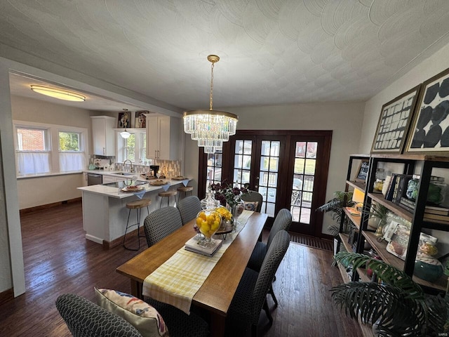 dining area with dark hardwood / wood-style flooring, sink, and a notable chandelier