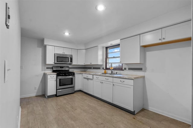 kitchen featuring sink, light hardwood / wood-style flooring, stainless steel appliances, and white cabinets