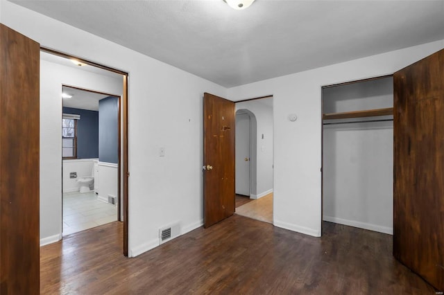 unfurnished bedroom with dark hardwood / wood-style flooring and a closet