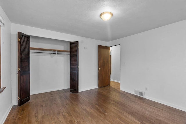 unfurnished bedroom featuring dark hardwood / wood-style floors and a closet