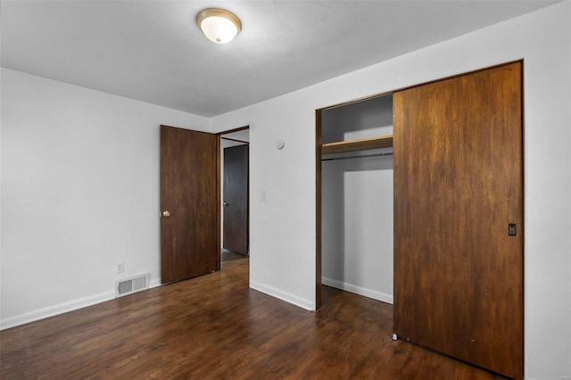 unfurnished bedroom featuring dark hardwood / wood-style floors and a closet