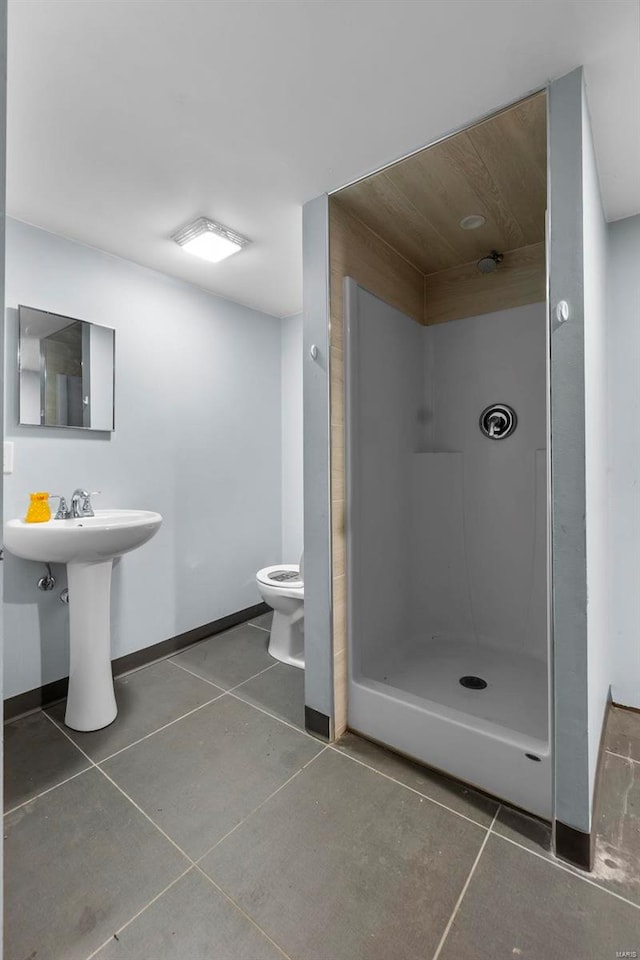 bathroom featuring toilet, tile patterned flooring, and a shower