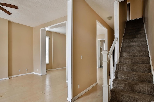 stairway featuring ceiling fan, hardwood / wood-style floors, and a textured ceiling