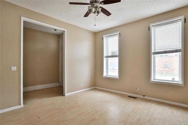 empty room with ceiling fan, a textured ceiling, and light wood-type flooring