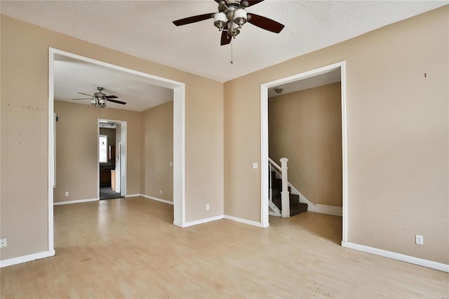 empty room with ceiling fan, a textured ceiling, and light wood-type flooring