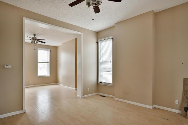 spare room with a healthy amount of sunlight, a textured ceiling, and light wood-type flooring