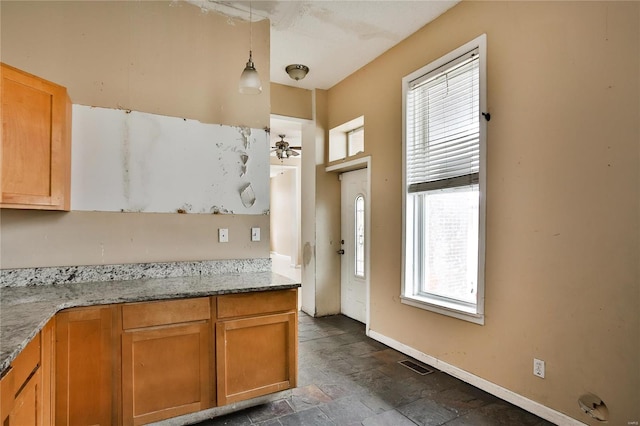 kitchen featuring ceiling fan, light stone countertops, and hanging light fixtures