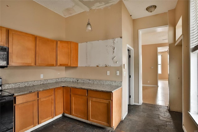 kitchen featuring a high ceiling, stove, hanging light fixtures, and light stone counters