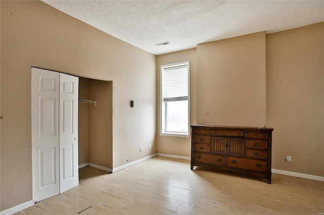 unfurnished bedroom with light hardwood / wood-style flooring, a closet, and a textured ceiling